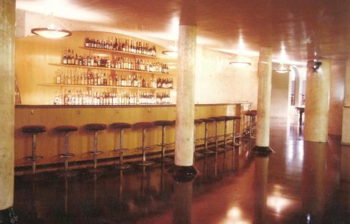 La barra vacía con su hilera de taburetes y el botellero al fondo